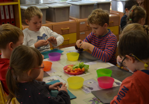 Dzieci z grupy IV obierają śliwki do sałatki